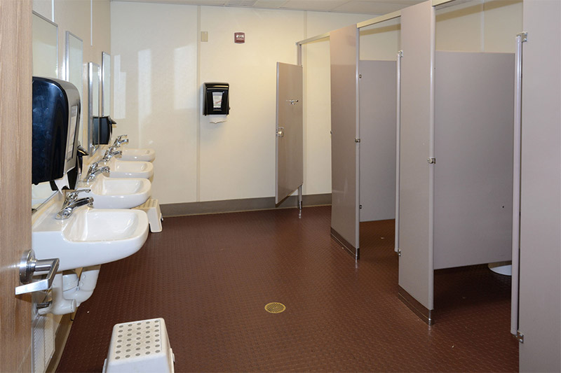 A bathroom displaying a sink and three urinals with tiled flooring in Pedricktown, NJ