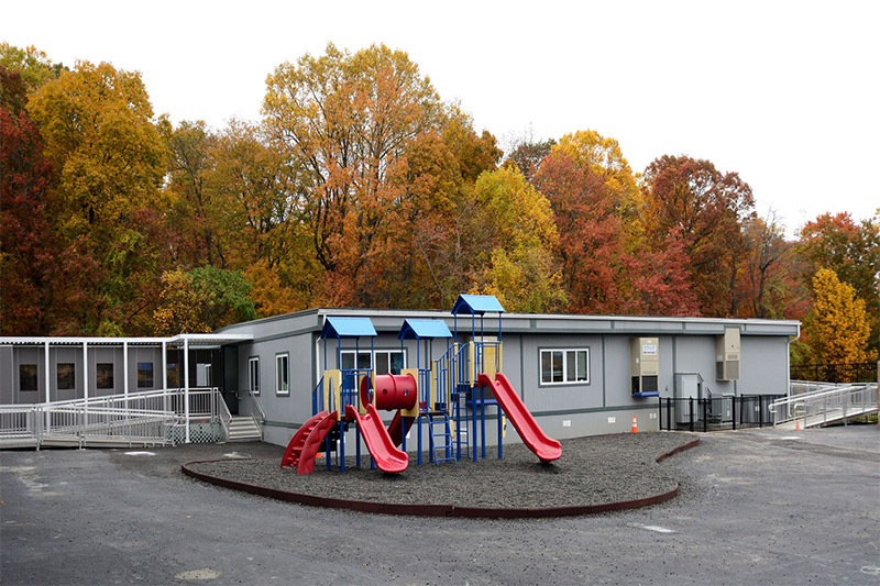 A playground set up in a parking lot surrounded by trees in Pedricktown, NJ